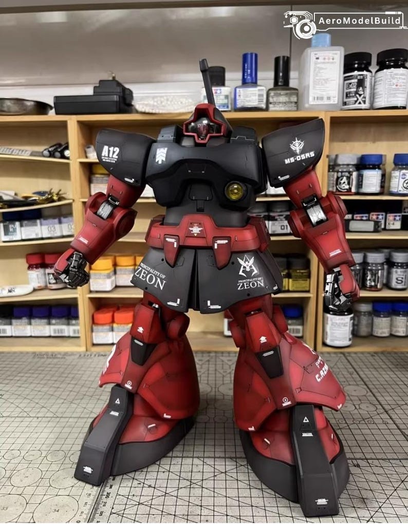 May include: A detailed model of a red and black robot with the text "ZEON" on the skirt armor. The robot has a distinctive head design and is posed with arms extended. The model is set against a backdrop of shelves with various bottles and containers.