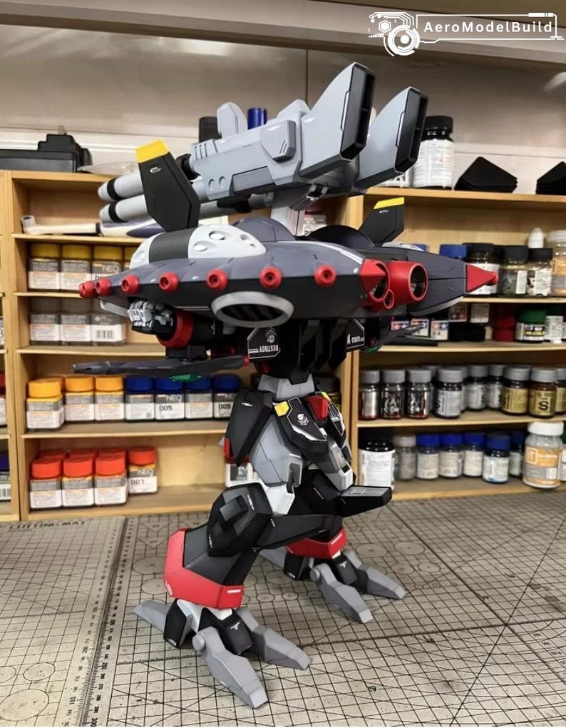 May include: A detailed model of a futuristic robot with a complex design. The model features a combination of gray, black, and red components, with multiple missile launchers and jet-like wings. The model is on a cutting mat.