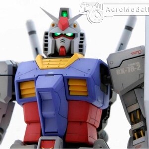 May include: A detailed model of a Gundam robot, featuring a color scheme of blue, red, yellow, and white. The robot has a detailed head with green glowing eyes and a red crest. The model includes a shield and is set against a white background.