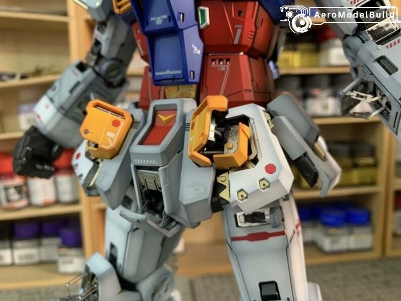 K&ouml;nnte beinhalten: Ein detailliertes, teilweise zusammengebautes Modell eines Roboters mit einem Farbschema aus Rot, Blau, Grau und Gelb. Der Torso und die Beine des Roboters sind sichtbar und zeigen komplizierte mechanische Details und Linien. Der Text "AeroModelBuild" ist sichtbar.