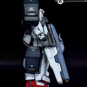 May include: A detailed model of a Gundam robot, featuring a color scheme of white, navy blue, and black. The robot has intricate panel lines and markings, with red accents on the feet. The image includes the text "GN 005 Gundam Virtue" and the logo "AeroModelBuild".