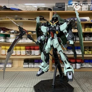 Puede incluir: Modelo detallado de un robot Gundam, principalmente en verde claro, negro y rojo. Est&aacute; posado con una gran guada&ntilde;a y alas, montado sobre un soporte negro. El fondo muestra estantes con botes de pintura.