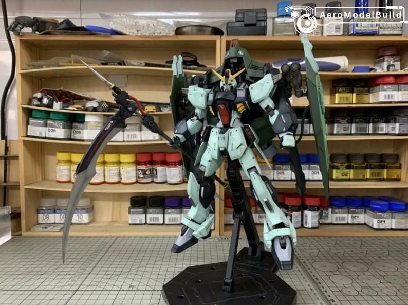Puede incluir: Modelo detallado de un robot Gundam, principalmente en verde claro, negro y rojo. Est&aacute; posado con una gran guada&ntilde;a y alas, montado sobre un soporte negro. El fondo muestra estantes con botes de pintura.