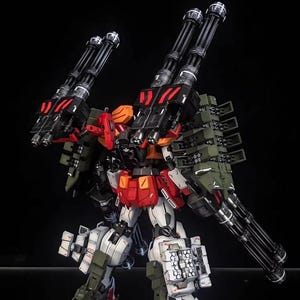May include: A detailed model of a mech robot, mainly white, red, black, and olive green. The robot has multiple large cannons and missile launchers attached to its back and arms. The AeroModelBuild logo is in the top right corner.