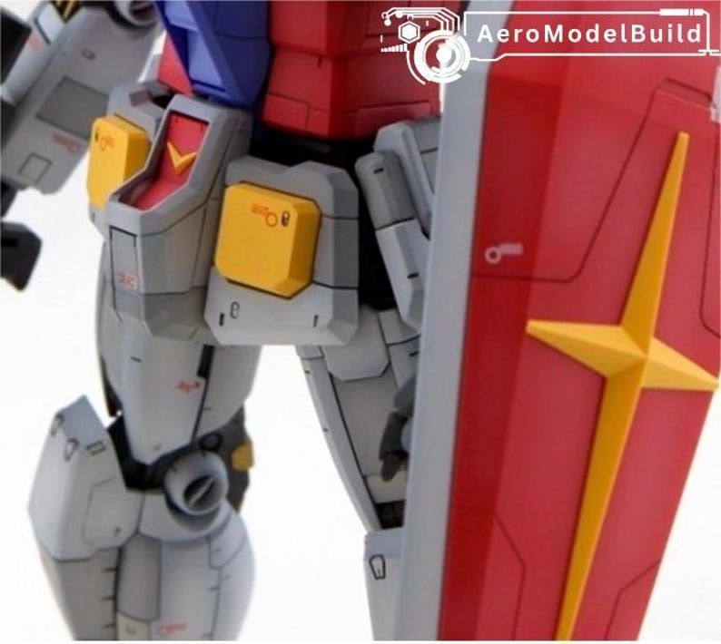 May include: Close-up of a detailed model robot, featuring a red shield with a yellow star design. The robot has gray, yellow, red, and blue components. The text "AeroModelBuild" is visible in the upper right corner.