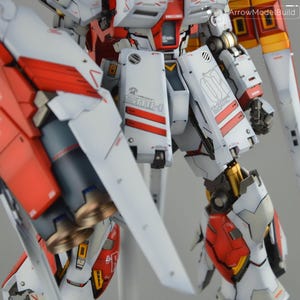 May include: Detailed model robot with white, red, and grey panels. The model features intricate mechanical details, including visible joints, vents, and text. The design incorporates red stripes and accents, with gold-coloured mechanical components.