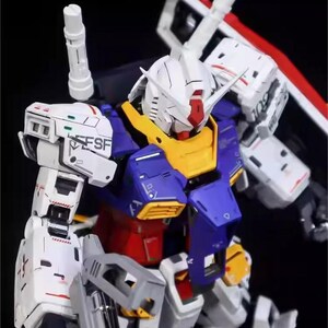 Op de afbeelding: Gedetailleerd model van een Gundam-robot, met een witte kop, rode en gele accenten, een blauwe en rode torso en grijze armen. Het model heeft ingewikkelde paneellijnen en markeringen, met de tekst "ESF" zichtbaar. Het AeroModelBuild-logo is zichtbaar.