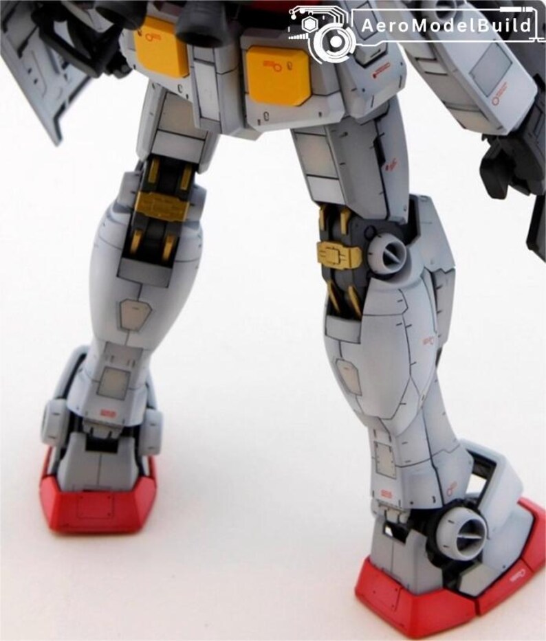 May include: Close-up of a detailed model robot's legs. The model features a color scheme of white, gray, red, and gold. The feet are red, and the joints are gold. The text "AeroModelBuild" is visible in the top right corner.