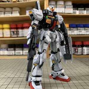 Pode incluir: Modelo detalhado de um rob&ocirc; Gundam, principalmente branco, cinza e preto, com detalhes em vermelho e amarelo. O modelo tem uma arma grande e um escudo. O texto "AG004" &eacute; vis&iacute;vel no ombro.