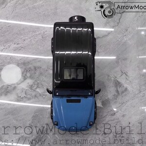 May include: Top-down view of a black and blue model car. The car has a black roof and a blue front. The image includes the text "ArrowModelBuild" and a website address.