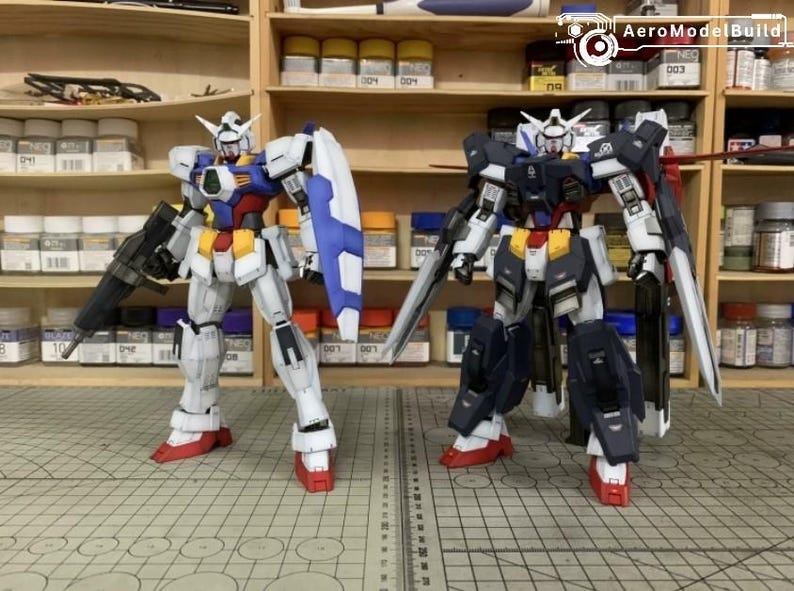 Puede incluir: Dos kits de modelos Gundam detallados. Uno es principalmente blanco, azul, rojo y amarillo, con una pistola negra y un escudo azul. El otro es azul oscuro, blanco, rojo y amarillo, con una espada grande. Ambos tienen pies rojos.