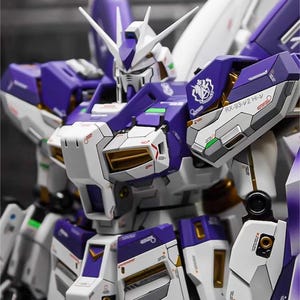 May include: A detailed model of a mecha robot, primarily white and purple, with gold accents. The robot has a complex design with multiple panels, sharp edges, and a detailed head. The image includes the text "AeroModelBuild".