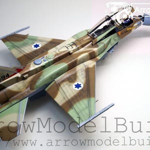 May include: A detailed model aircraft in camouflage colours, featuring Israeli Air Force markings. The model has a detailed cockpit and wings, with the number "494" visible on the tail. The model is set against a white background.