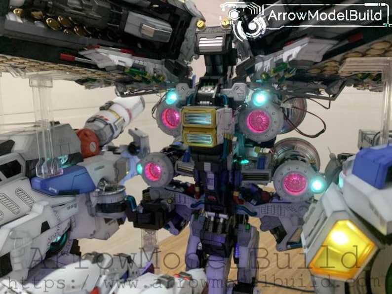 May include: A detailed model of a futuristic robot with multiple components. The model features a combination of white, blue, gray, and yellow parts, with glowing pink and blue lights. The text "ArrowModelBuild" is visible.