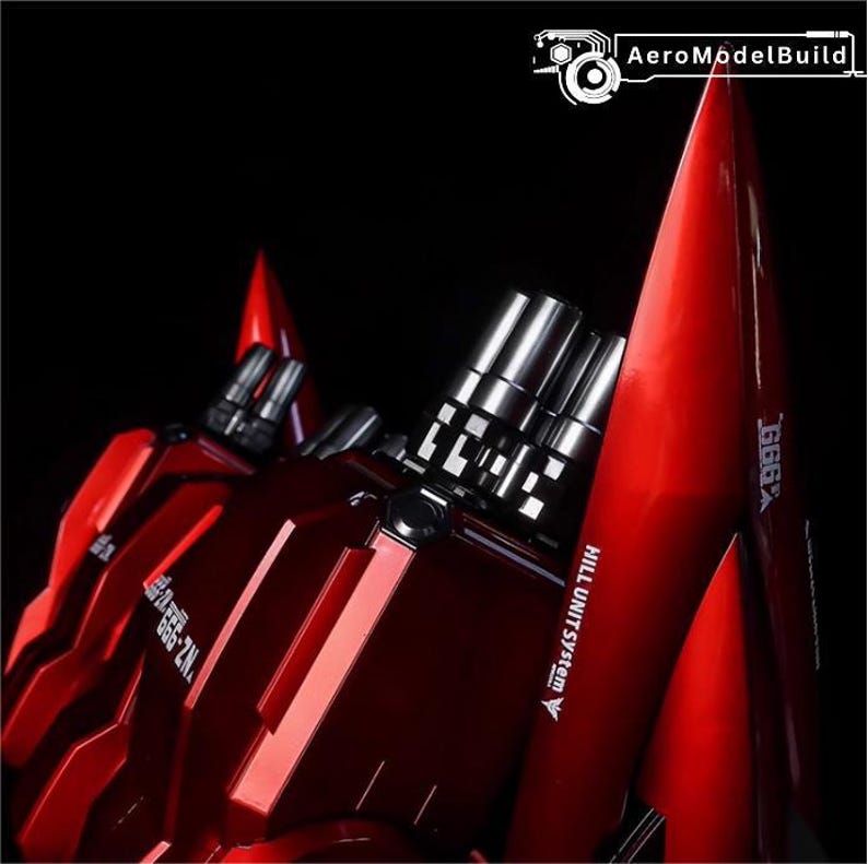 May include: A close-up of a red model robot with silver metallic accents. The model has sharp angles and a glossy finish. Text on the model reads "GGG X" and "HILL UNIT SYSTEM". The background is black.