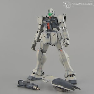 Puede incluir: Un modelo detallado de un robot blanco y gris con detalles en rojo y verde. El robot tiene extremidades articuladas y está de pie con una pieza separada y un arma en el suelo. El modelo lleva el texto "ArrowModelBuild".