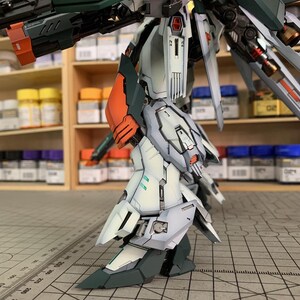 May include: A detailed model of a robot with a complex design. The robot features a color scheme of white, green, orange, and gray. The image includes the text "ArrowModelBuild" and a website address.