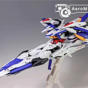 Puede incluir: Maqueta de avi&oacute;n AeroModelBuild. El modelo es blanco, azul, rojo y amarillo. El avi&oacute;n est&aacute; sobre un soporte transparente. El texto "AeroModelBuild" est&aacute; en la esquina superior derecha.