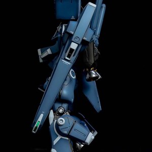 May include: A side view of a detailed, dark blue model robot with articulated joints and panels. The model has a complex design with various mechanical components, including a large weapon and a backpack. The text "AeroModelBuild" is visible in the upper right corner.