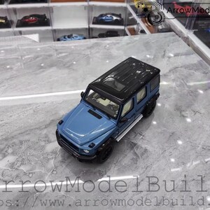 May include: A blue and black diecast model SUV. The model has a black roof, black tires, and silver side steps. The vehicle is on a marble-like surface. The text "ArrowModelBuild" and a website address are visible.