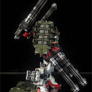 May include: A detailed model of a mech robot, with white, red, black, and olive green components. The robot has multiple large-caliber cannons and missile launchers, demonstrating a complex design. The AeroModelBuild logo is visible.