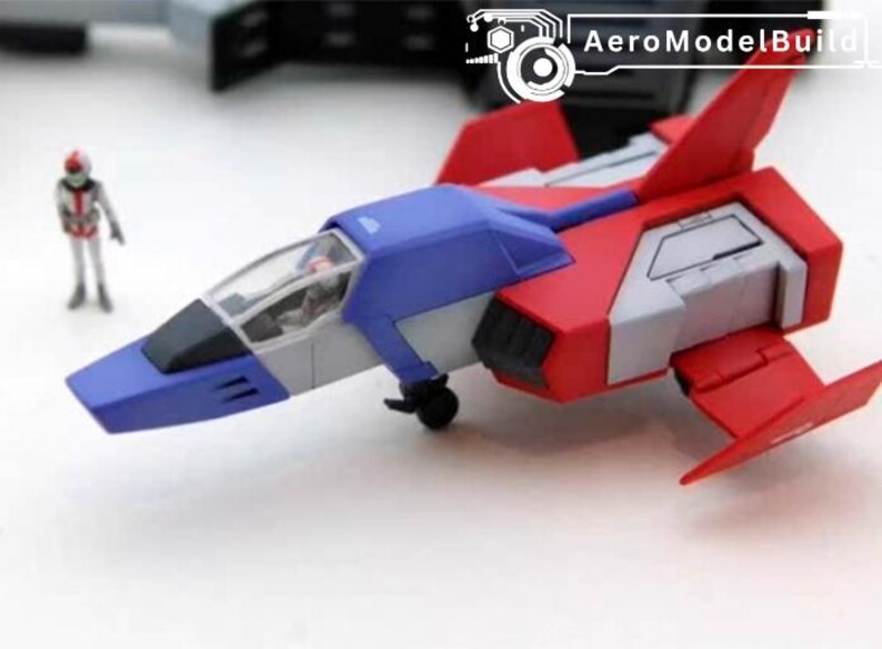 May include: AeroModelBuild model airplane in red, blue, and white. The toy plane has a cockpit and wings, and is next to a small figurine. The plane is on a white surface.