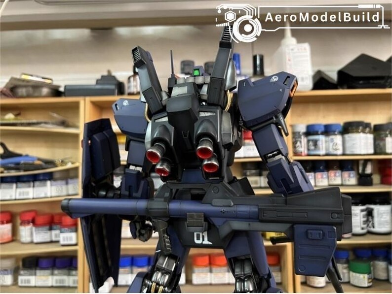 Pu&ograve; includere: Un modello di robot blu scuro con una grande arma e uno scudo. Il robot ha dettagli rossi sui suoi propulsori e il numero "01" &egrave; visibile. Il testo "AeroModelBuild" &egrave; visibile. Il modello &egrave; su uno scaffale.