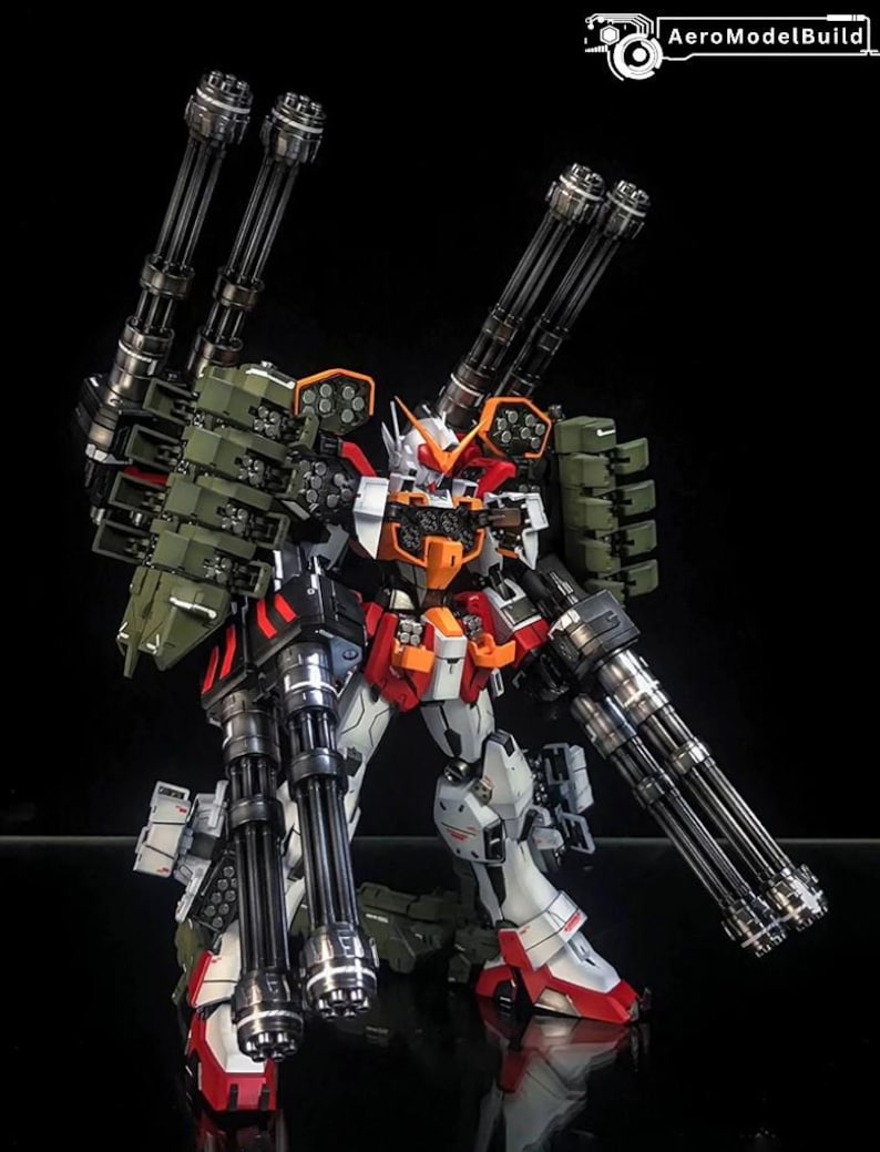 K&ouml;nnte beinhalten: Eine detailreiche Roboter-Actionfigur in den Farben Wei&szlig;, Rot und Orange. Sie ist mit vier gro&szlig;en schwarzen mehrl&auml;ufigen Kanonen, olivgr&uuml;nen Raketenwerfern und Panzerplatten ausgestattet. Der Text AeroModelBuild ist zu sehen.