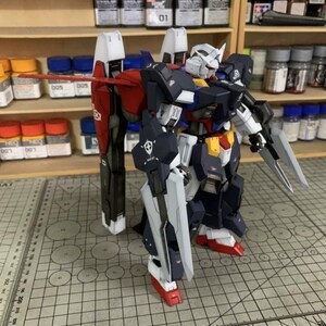 Puede incluir: Maqueta detallada de un robot Gundam, con una combinaci&oacute;n de colores azul marino, blanco, rojo y amarillo. El robot tiene extremidades grandes y articuladas, una cabeza con cresta blanca y est&aacute; equipado con un escudo y una espada. El modelo est&aacute; sobre una superficie cuadriculada.