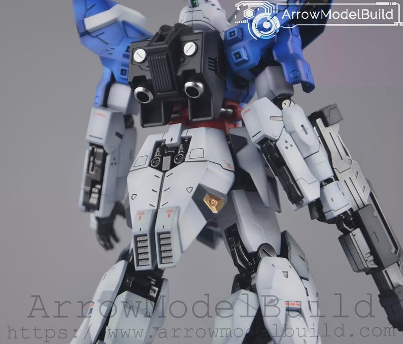May include: A detailed model kit of a mecha robot, with a colour scheme of white, blue, black, and red. The robot has intricate mechanical details, including panels, vents, and weapon attachments. The image includes the text "ArrowModelBuild".