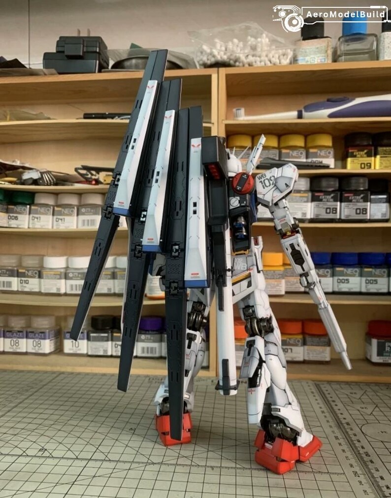 K&ouml;nnte beinhalten: Ein detailliertes Modell eines wei&szlig;en, schwarzen und roten Mecha-Roboters. Der Roboter hat gro&szlig;e Fl&uuml;gel und steht auf einer Rasteroberfl&auml;che. Der Hintergrund zeigt Regale mit Farben und Modellbauwerkzeugen.