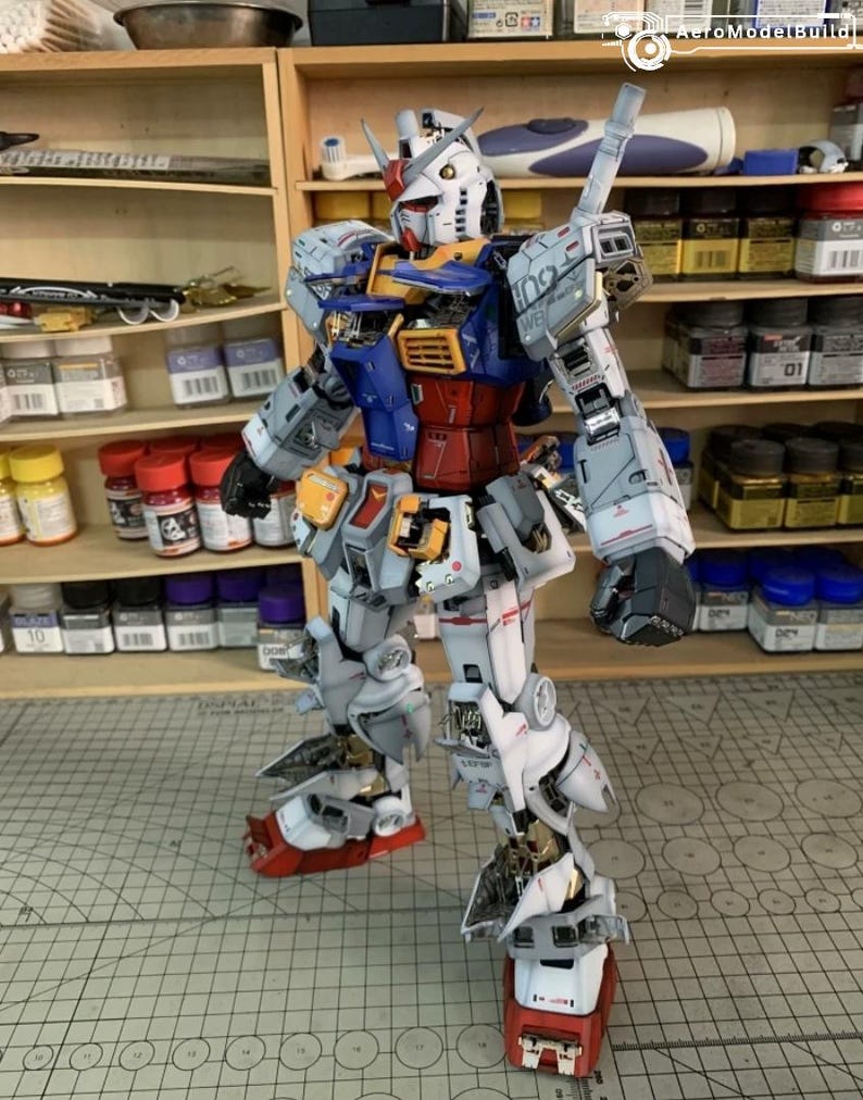 K&ouml;nnte beinhalten: Ein detailliertes Modell eines Gundam-Roboters mit einem Farbschema aus Wei&szlig;, Blau, Rot und Gelb. Das Modell steht aufrecht und zeigt komplizierte mechanische Details und Linien. Die F&uuml;&szlig;e des Roboters sind rot und wei&szlig;, und das Modell steht auf einer Rasteroberfl&auml;che.