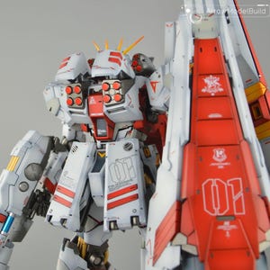 May include: A detailed model of a white and red mecha robot with intricate designs. The robot features multiple missile launchers, yellow accents, and the text "FA-93 HWS" and "01". The model is a complex assembly.