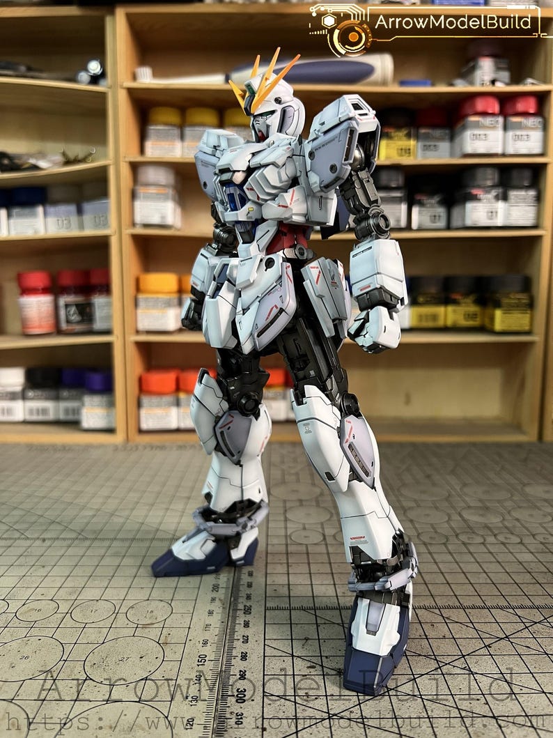 May include: A detailed, articulated model robot in white, gray, and black, with red accents. The model has a complex design with multiple panels and joints. The text "ArrowModelBuild" is visible in the top right corner.
