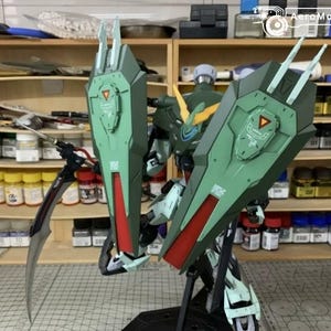 Puede incluir: Kit de modelo detallado de un robot Gundam, con una combinaci&oacute;n de colores verde y rojo. El robot tiene escudos grandes y angulares y una cuchilla curva. El modelo se exhibe frente a una estanter&iacute;a llena de pinturas y herramientas.