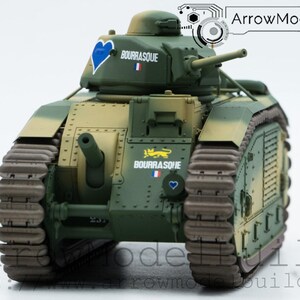 Puede incluir: Maqueta detallada de un tanque en verde oliva, beige y marrón, con el texto "BOURRASQUE" y un emblema de corazón azul. El modelo tiene una torreta, dos cañones y orugas. También es visible la bandera francesa.