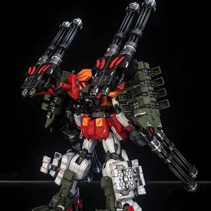 K&ouml;nnte beinhalten: Ein hochdetailliertes Mecha-Modell in den Farben Wei&szlig;, Rot und Olivgr&uuml;n. Die Figur ist mit mehreren gro&szlig;en schwarzen Gatling-Kanonen an den Schultern und am R&uuml;cken sowie mit Raketenwerfern und schwerer Panzerung ausgestattet.