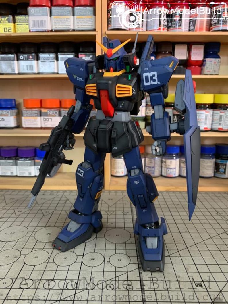 May include: A detailed model of a dark blue and black mecha robot with orange and red accents. The robot has a shield, a rifle, and the number "03" is visible on its body. The background includes shelves with paint bottles and the text "ArrowModelBuild".