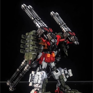 May include: A detailed model of a mech robot with multiple gun barrels and missile launchers. The robot is primarily white, red, and green, with silver gun barrels. The AeroModelBuild logo is in the top right corner.