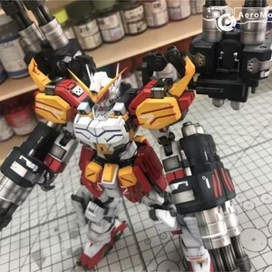 K&ouml;nnte beinhalten: Detailliertes Modell eines Roboters in Wei&szlig;, Rot und Gelb. Der Roboter hat gro&szlig;e Kanonen und steht auf einer Schneidematte. Das AeroModelBuild-Logo ist oben rechts sichtbar.