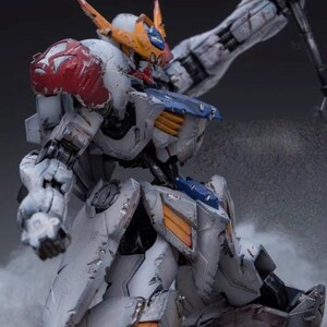May include: A detailed model of a mecha robot, primarily white with accents of red, blue, and orange. The robot is posed dynamically, with a weapon raised. The model has a weathered appearance, suggesting battle damage. The text "ArrowModelBuild" is visible.