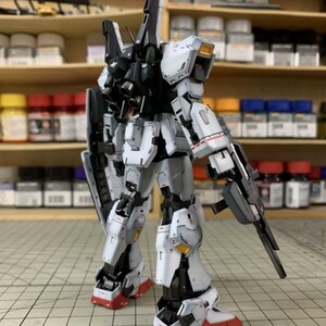 Pode incluir: Um modelo detalhado de um rob&ocirc; mecha branco, cinza, preto e vermelho com uma arma e um escudo. O modelo tem detalhes intrincados e est&aacute; posicionado em uma superf&iacute;cie de grade. O texto "AeroModelBuild" &eacute; vis&iacute;vel.
