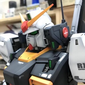 Op de afbeelding: Een gedetailleerd model van een Gundam-robot, met een witte kop en rode en gele accenten. Het model heeft zwarte en gele bepantsering, met groene en rode details. De tekst "AeroModelBuild" is zichtbaar in de rechterbovenhoek.