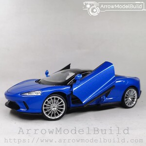 Op de afbeelding: Een blauwe modelauto met open deuren, die het interieur laten zien. De auto heeft zilveren velgen en een zwart dak. Dit is een miniatuur replica van een sportwagen.
