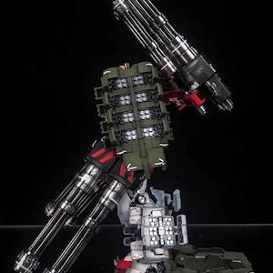 May include: AeroModelBuild model kit of a detailed robot with multiple parts. The model features silver, black, red, white, and green components, including large cannons and missile launchers. The logo "AeroModelBuild" is visible on the image.