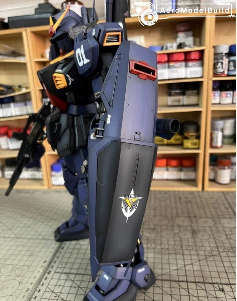 Pu&ograve; includere: Modello dettagliato di un robot mecha blu scuro e nero con accenti arancioni e rossi. Il robot ha uno scudo con un logo e il numero "01" sulla spalla. Lo sfondo include scaffali con varie bottiglie e contenitori.