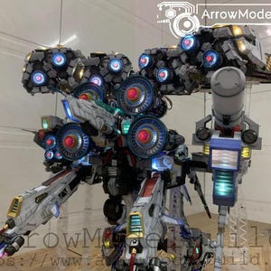 May include: A detailed model of a futuristic robot with multiple components, including large circular elements with red and blue lights. The model is primarily white, gray, and blue, with accents of yellow and green. The text "ArrowModelBuild" is visible.