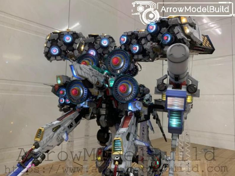 May include: A detailed model of a futuristic robot with multiple components, including large circular elements with red and blue lights. The model is primarily white, gray, and blue, with accents of yellow and green. The text "ArrowModelBuild" is visible.