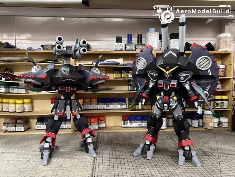 May include: Two detailed model robots, one with multiple cannons and the other with large circular shoulder armor. The robots are primarily black, red, and gray, with intricate designs and details. The background shows shelves with various tools and supplies.