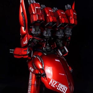 May include: A detailed, red model of a futuristic robot with multiple thrusters and the text "NZ-999". The model has a glossy finish and intricate mechanical details, set against a black background.